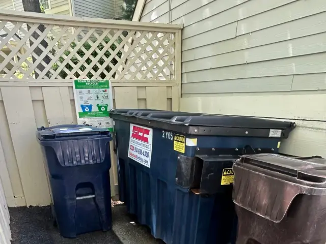 Commercial dumpster enclosure on a concrete pad beside a building