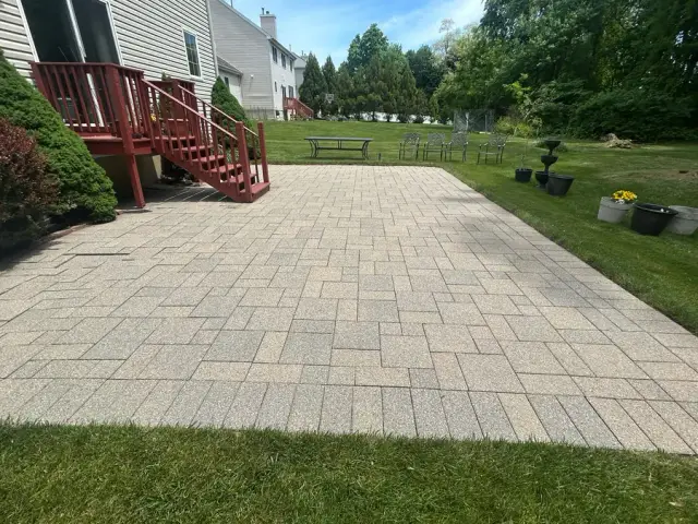 Freshly cleaned paver patio behind a home, ready for furniture